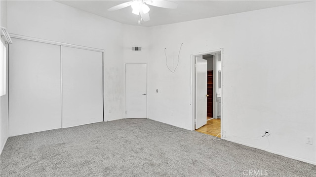 unfurnished bedroom with ceiling fan, light colored carpet, and a closet