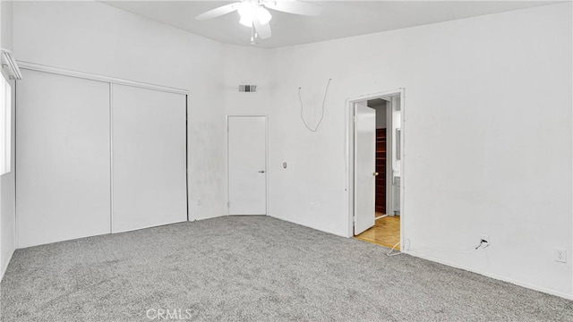 unfurnished bedroom with a closet, visible vents, carpet flooring, and a ceiling fan