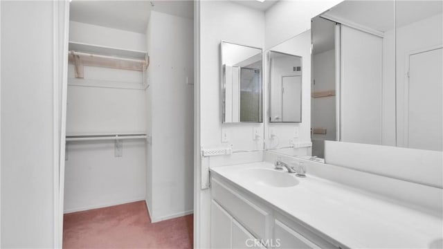 bathroom featuring baseboards, vanity, and a walk in closet