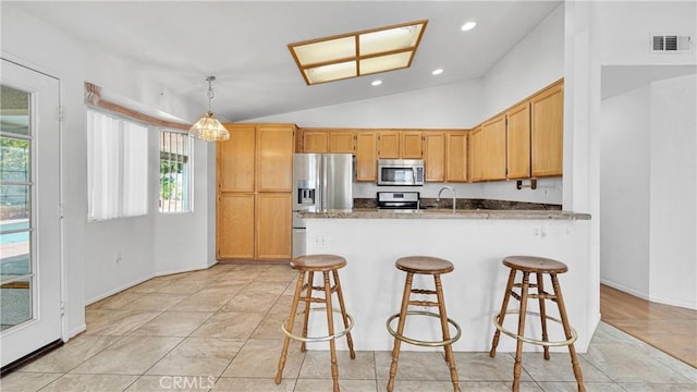 kitchen with a kitchen breakfast bar, vaulted ceiling, visible vents, a peninsula, and appliances with stainless steel finishes