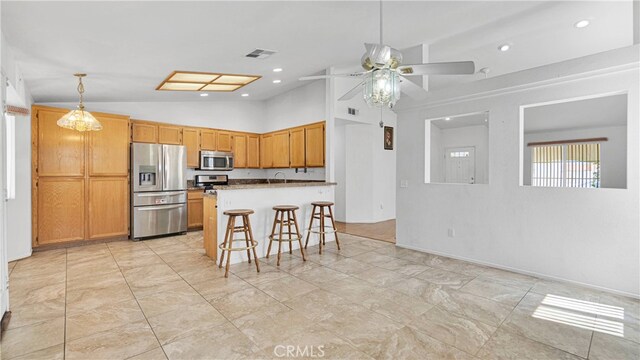 kitchen with a breakfast bar, stainless steel appliances, lofted ceiling, a center island, and ceiling fan