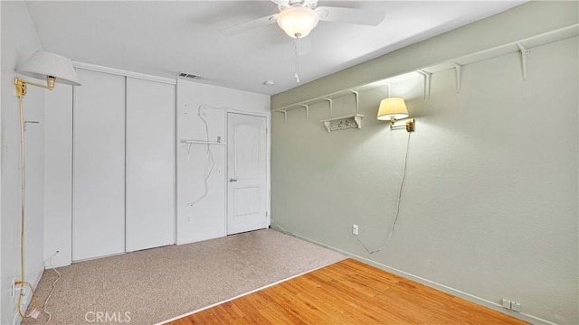 unfurnished bedroom featuring a ceiling fan, wood finished floors, visible vents, and a closet