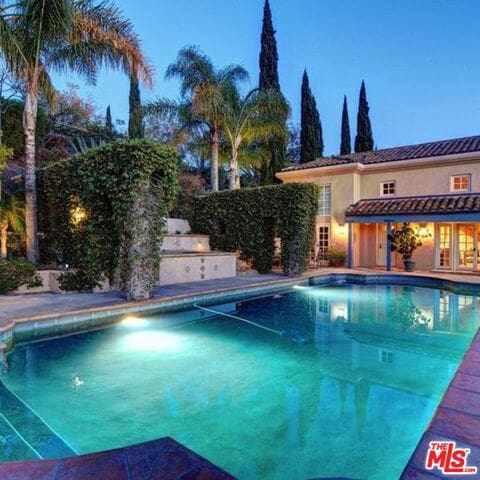 pool at dusk with exterior kitchen