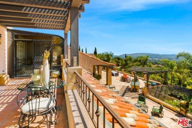 balcony featuring a mountain view and a pergola