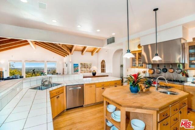 kitchen featuring vaulted ceiling with beams, decorative light fixtures, stainless steel dishwasher, and sink