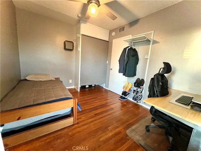 bedroom with a closet, ceiling fan, a textured ceiling, and dark wood-type flooring