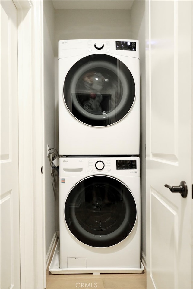 laundry area with stacked washer and clothes dryer and hardwood / wood-style floors