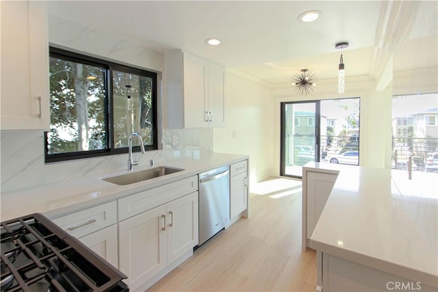 kitchen featuring sink, white cabinets, stainless steel dishwasher, and decorative light fixtures