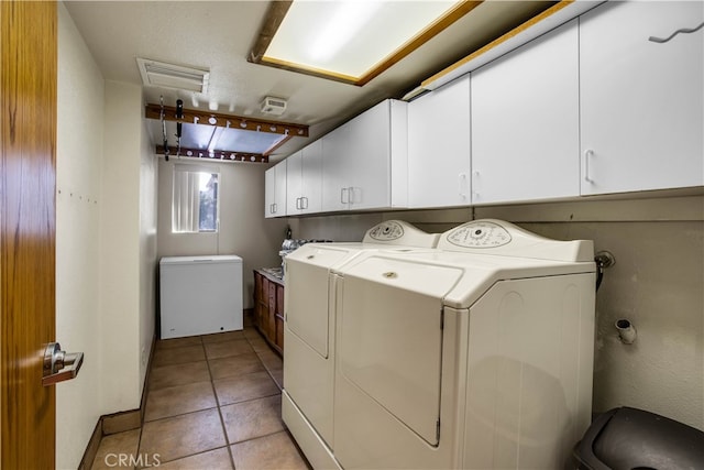 laundry area with washer and clothes dryer, cabinets, and light tile patterned floors