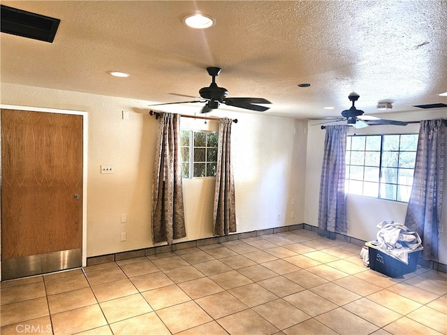 empty room featuring ceiling fan, a textured ceiling, and light tile patterned floors