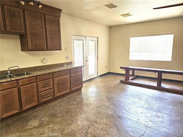 kitchen with a textured ceiling, dark brown cabinets, sink, and ceiling fan