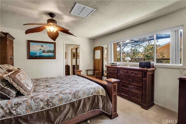 bedroom featuring a textured ceiling, light carpet, and ceiling fan