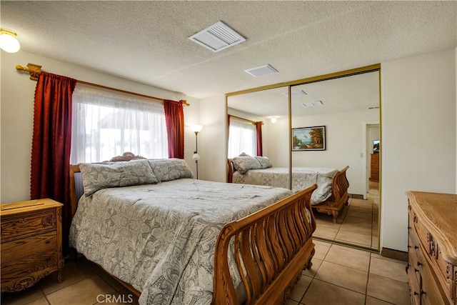 tiled bedroom with a textured ceiling and a closet