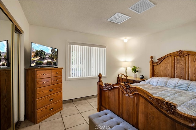 tiled bedroom with a closet and a textured ceiling