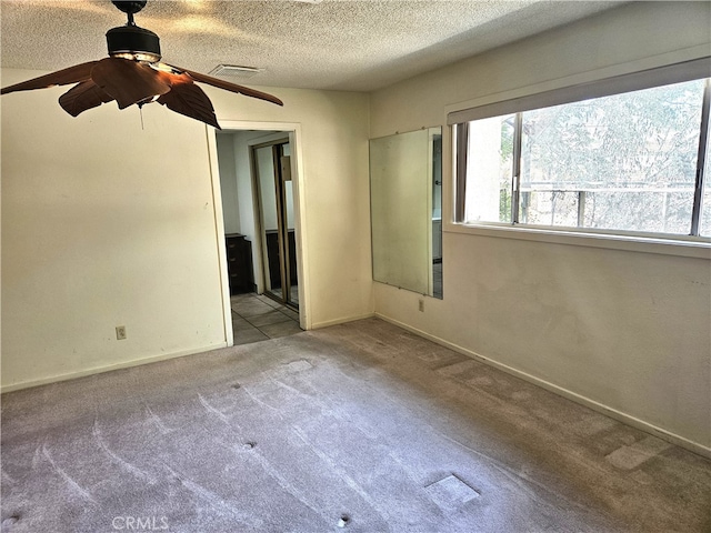 unfurnished bedroom featuring light carpet, ceiling fan, and a textured ceiling