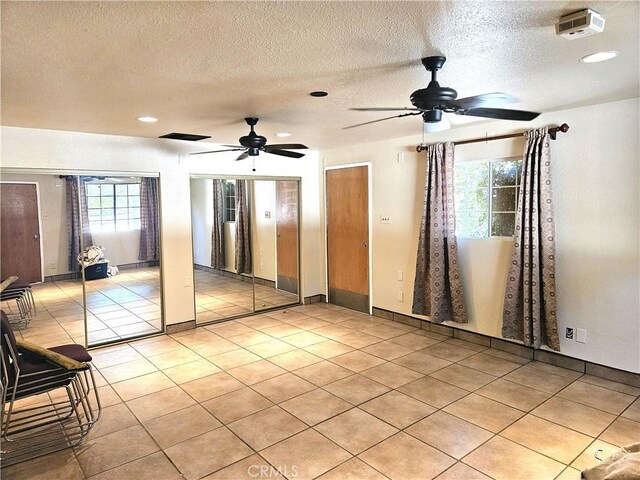 tiled spare room with a textured ceiling and ceiling fan