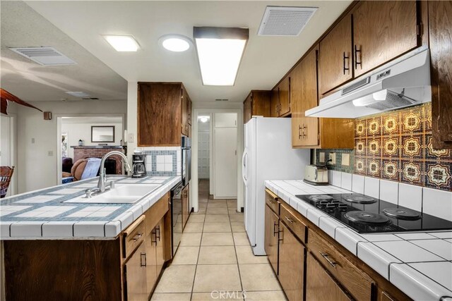 kitchen featuring light tile patterned floors, sink, tasteful backsplash, black appliances, and tile countertops