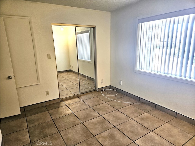 unfurnished bedroom featuring a closet, tile patterned floors, and a textured ceiling