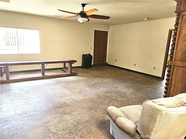 living room featuring ceiling fan and a textured ceiling