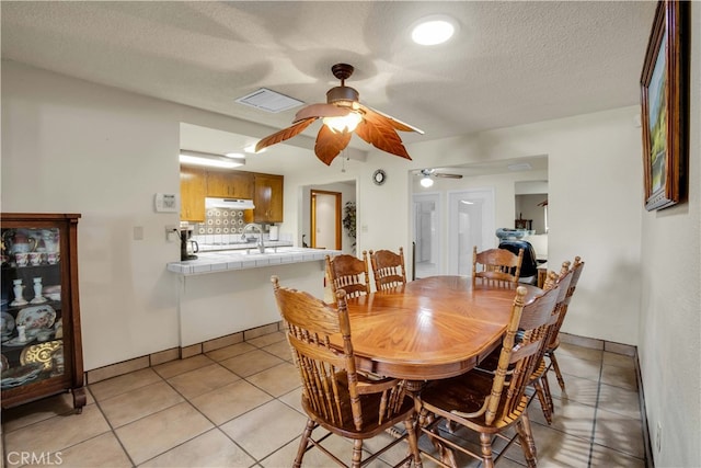 dining space featuring a textured ceiling, ceiling fan, and light tile patterned floors