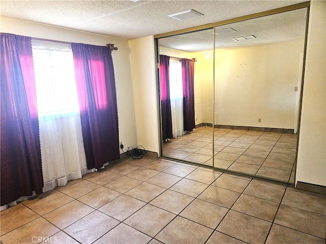 spare room featuring a textured ceiling and light tile patterned flooring