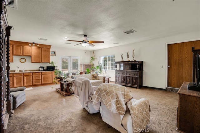 living room featuring ceiling fan, a textured ceiling, sink, and french doors