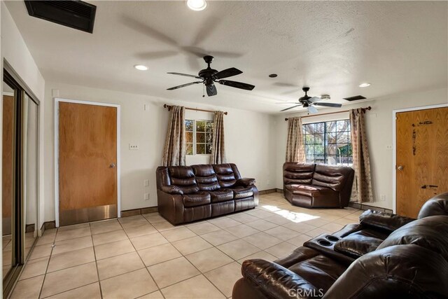 tiled living room with ceiling fan and a textured ceiling