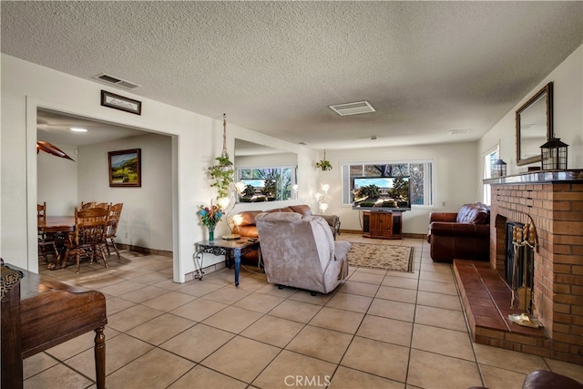 tiled living room featuring a brick fireplace, a textured ceiling, and plenty of natural light