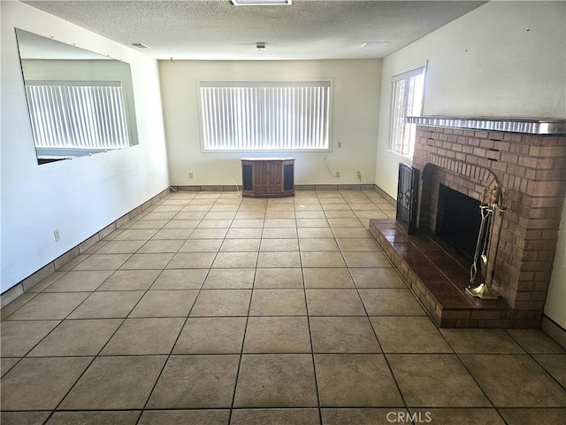 unfurnished living room with a textured ceiling, tile patterned flooring, and a brick fireplace