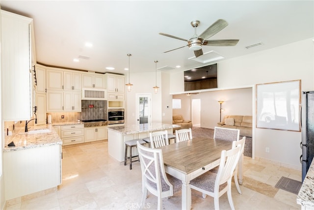 dining space featuring ceiling fan and sink