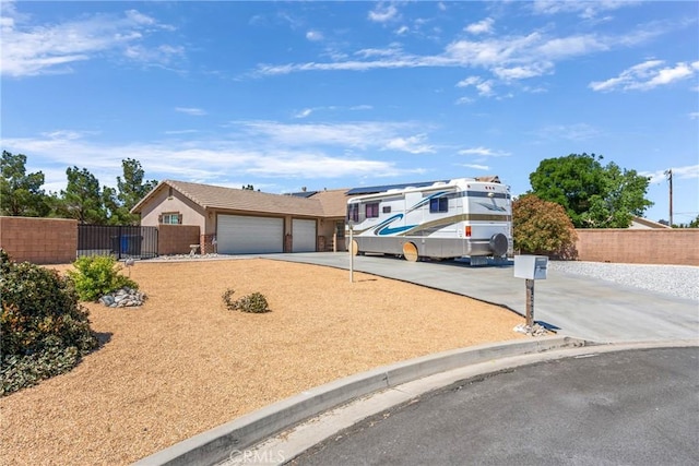 view of front of house featuring concrete driveway, fence, an attached garage, and a gate