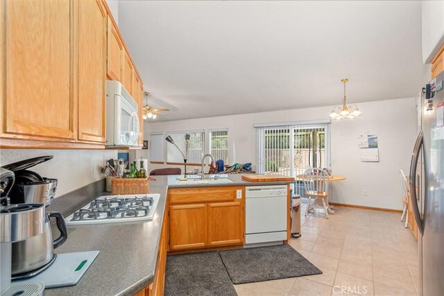 kitchen featuring sink, ceiling fan with notable chandelier, hanging light fixtures, white appliances, and light tile patterned floors