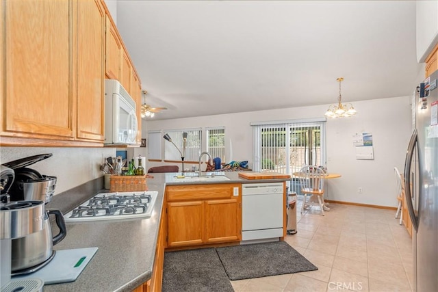 kitchen with a peninsula, white appliances, a sink, and a healthy amount of sunlight