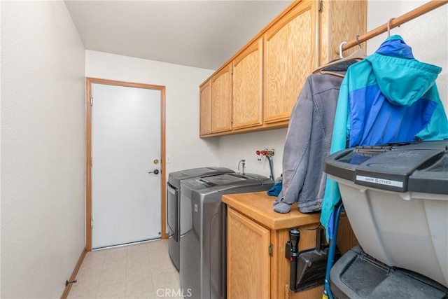 washroom with cabinet space, washing machine and dryer, and baseboards