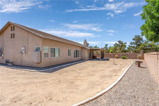 rear view of house featuring a patio area, a fenced backyard, and stucco siding