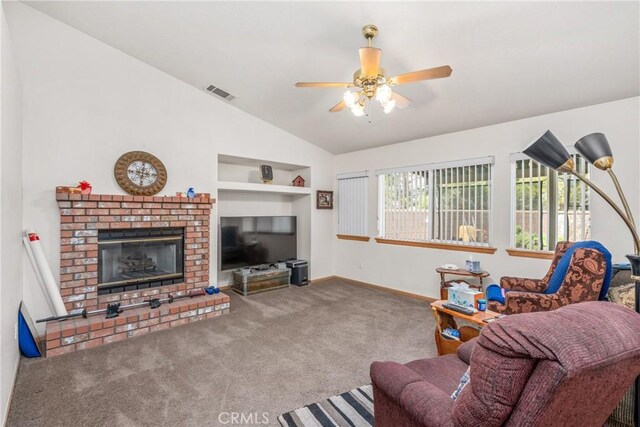 carpeted living room featuring a brick fireplace, vaulted ceiling, ceiling fan, and built in shelves