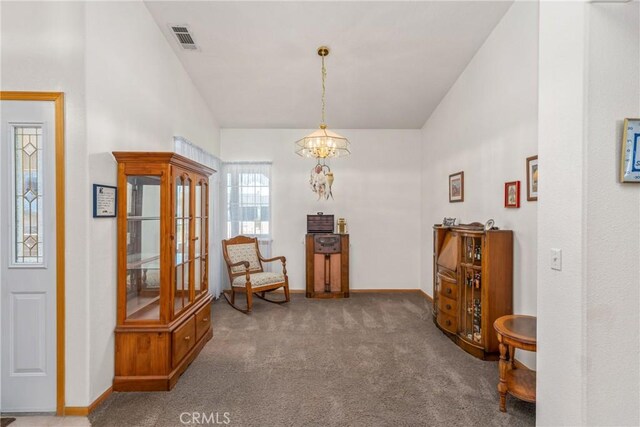 sitting room featuring an inviting chandelier, vaulted ceiling, and carpet flooring