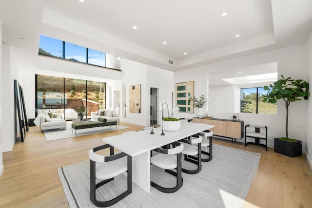 dining space featuring a tray ceiling and light hardwood / wood-style flooring