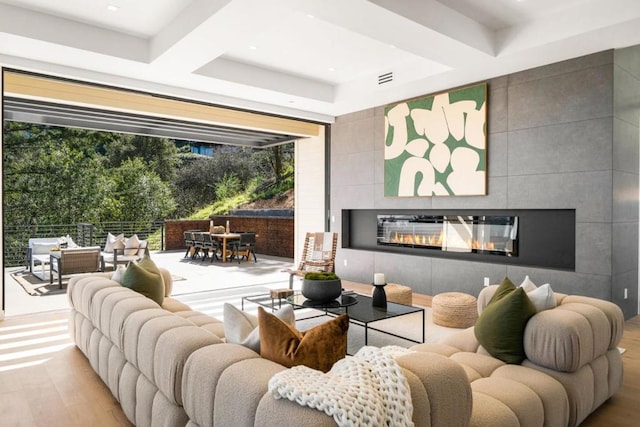 living room with coffered ceiling, light hardwood / wood-style flooring, and a tile fireplace