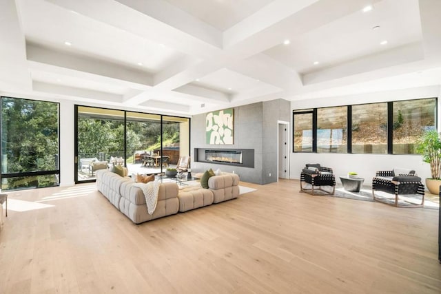 living room featuring a tiled fireplace, coffered ceiling, light wood-type flooring, and beamed ceiling