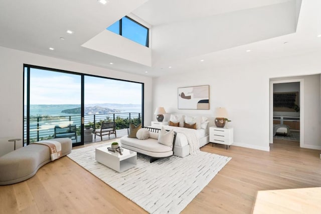 bedroom with a water and mountain view, access to exterior, and light hardwood / wood-style floors