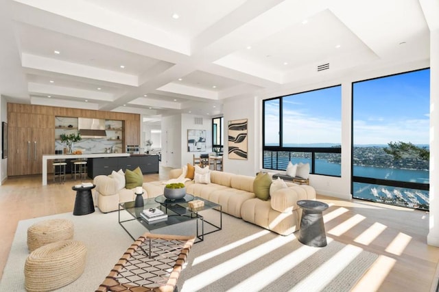 living room with light wood-type flooring, beamed ceiling, and a water view