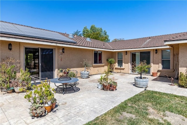 rear view of property with solar panels and a patio