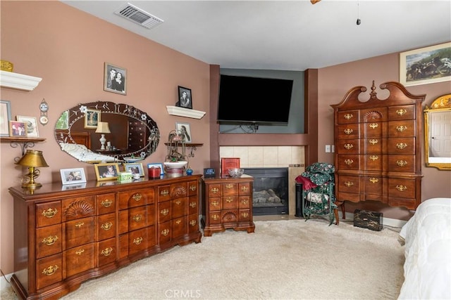 bedroom featuring a tile fireplace and light carpet