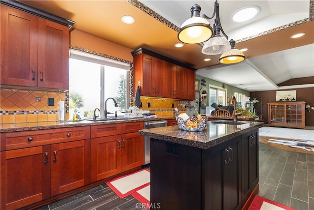 kitchen featuring tasteful backsplash, stainless steel dishwasher, vaulted ceiling, sink, and dark stone countertops