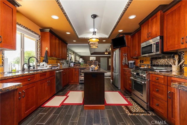 kitchen with a center island, sink, dark stone countertops, dark hardwood / wood-style flooring, and stainless steel appliances