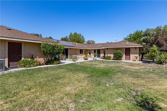 ranch-style home featuring a front lawn and solar panels