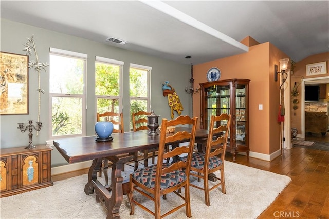 dining area featuring dark hardwood / wood-style floors and vaulted ceiling