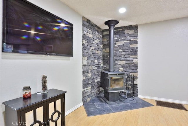 room details featuring wood-type flooring, a wood stove, and a textured ceiling