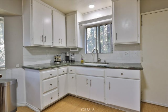 kitchen featuring backsplash, light hardwood / wood-style floors, white cabinetry, and sink